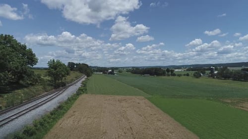 Luftaufnahme von Ackerland und Landschaft mit einer Eisenbahnstrecke an einem schönen sonnigen Sommertag