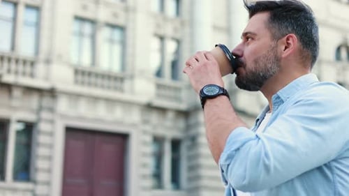 Portrait of Stylish Handsome Caucasian Young Man Walking in the City and Drinking Coffee to Go While