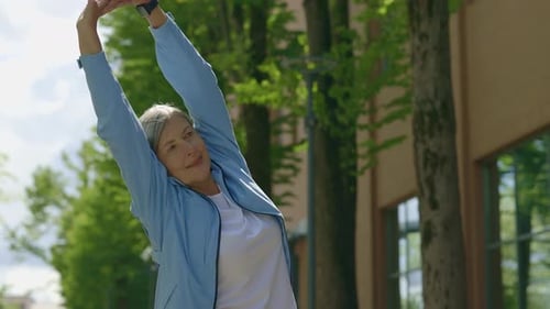 Mature Woman Stretching Arms on Pathway