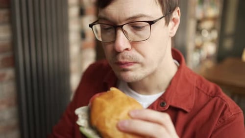 Man Eating Burger and Drinking Beer at Restaurant