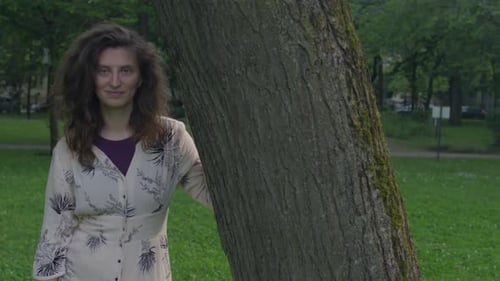 Woman Leaning on Tree in Green Urban Park