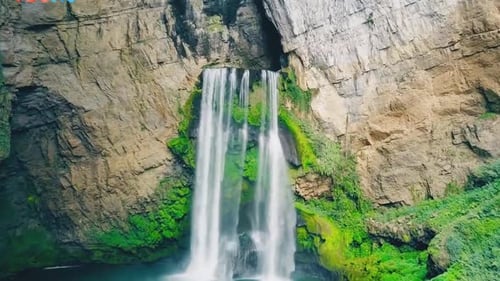 Majestic Waterfall Cascading Down Mossy Rock Cliffs In Lush Green Wilderness