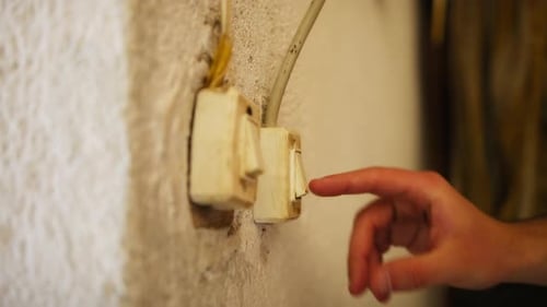 Mão de um menino toca um interruptor de luz vintage