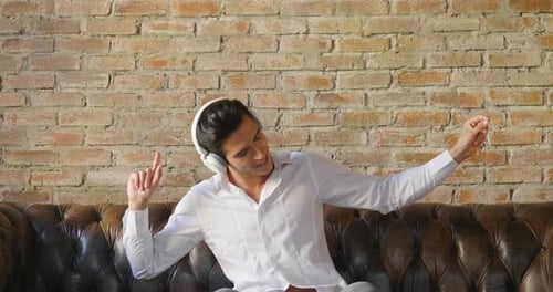 A boy listens to music with headphones on the couch of his loft. She closes her eyes and plunges i