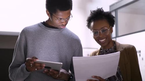 Business People With Digital Tablet Reviewing Paperwork In Office