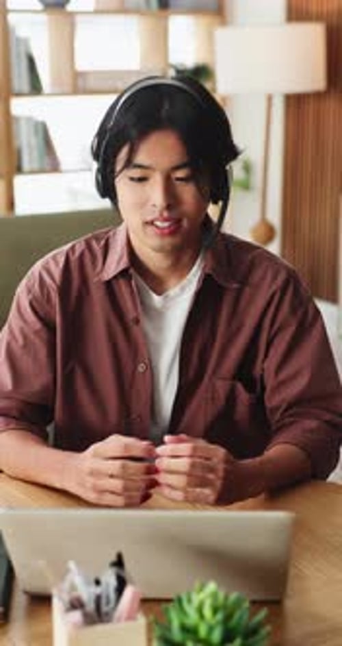 Young Man Attending Virtual Meeting at Wooden Desk