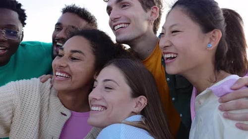 Groupe diversifié d'amis de la génération Y ayant un appel Vidéo au téléphone à l'extérieur