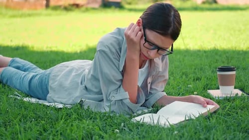 Estudiante adolescente leyendo sus libros acostada al aire libre de regreso a la escuela soñando