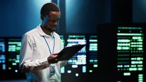 African American System Administrator Inspecting Server Clusters Inside Data Center