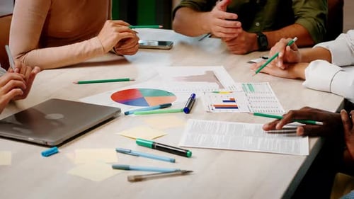 Das Team von Büroangestellten diskutiert Diagramme und Grafiken auf Papieren