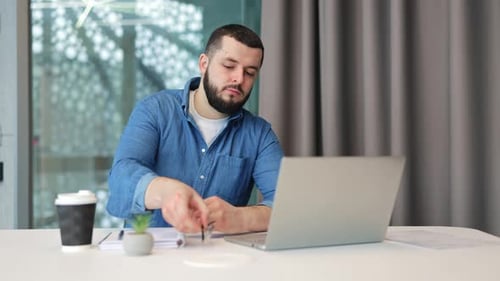 Man works on laptop in modern office setting