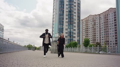 Friends Walking Boldly on Modern City Promenade Near Tall Buildings