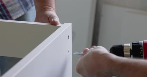 Man Assembling Furniture in Home with Screw Driver