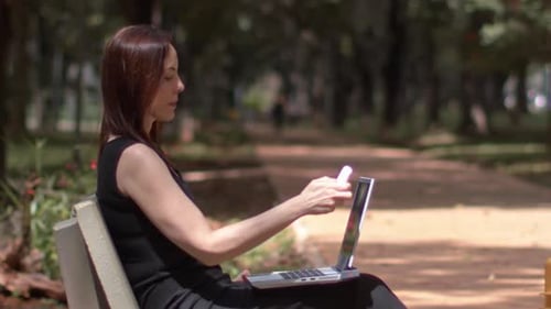 Junge Frau öffnet ihren tragbaren Computer und arbeitet im Stadtpark.
Zeitlupe