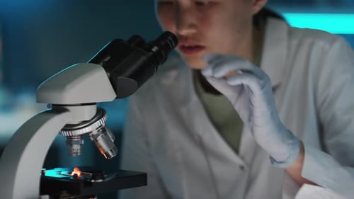 Woman Using Microscope in Blue Lit Lab