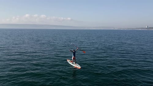 Aerial View of a Man Paddling a Standup Paddleboard or SUP Board on a Calm Sea
