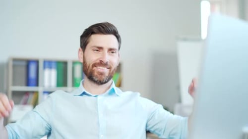 Smiling Man Relaxes in Office After Finishing Task