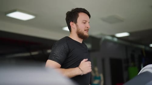 Homem caucasiano barbudo corre em academia coberta, esteira, treinamento de resistência
