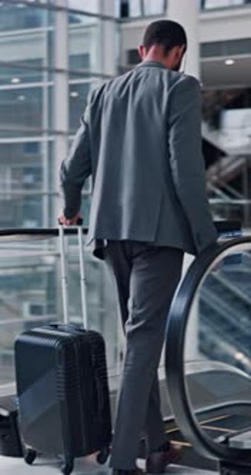 Man in Suit Walking with Luggage in Airport