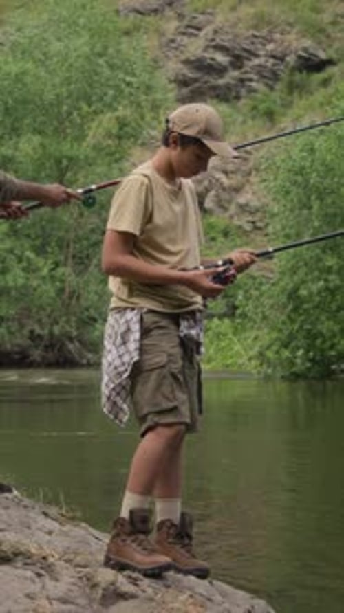 Vertical of Teenage Asian Boy Learning Angling Skills while Fishing with Dad