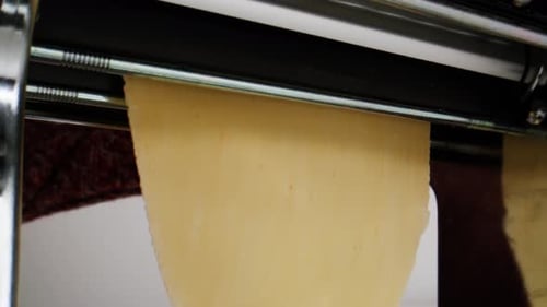 Woman Using Pasta Machine to Make Fresh Pasta Dough in the Kitchen Cooking in Italian Restaurant