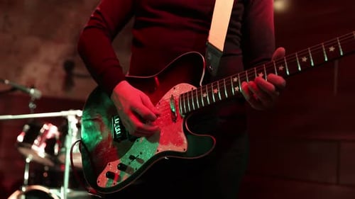 Man Playing Electric Guitar on Stage at Music Venue