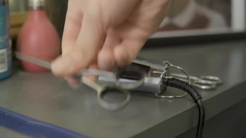 Barber picking up hair trimmer and scissors at barbershop in central London.