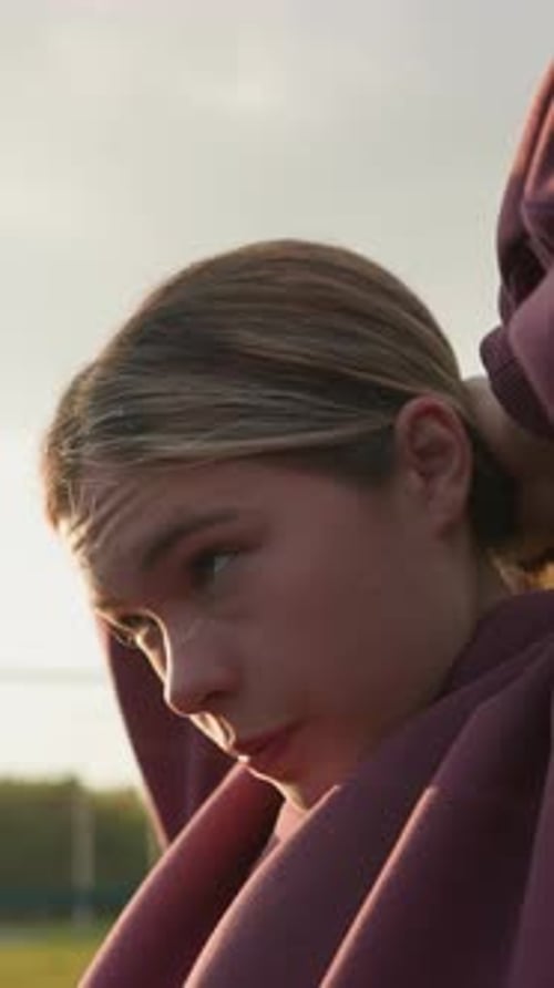 Side View Woman Tying Hair Backward Outdoors with Sunlight Creating Glow