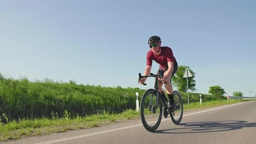 Cyclist Riding Past at High Speed on Roadway in Countryside