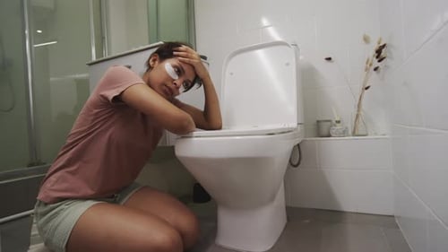 Fille malade souffrant d'une intoxication alimentaire s'appuyant sur les toilettes dans la salle de bain