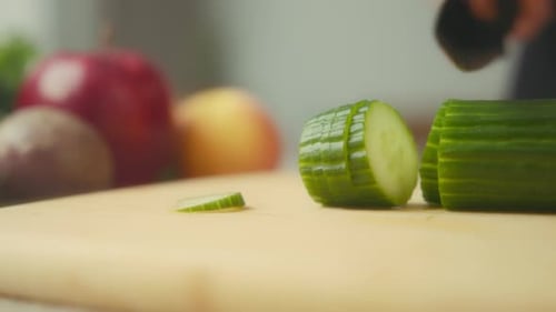 Slicing a Cucumber with Sharp Knife on Cutting Board