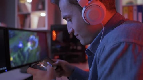 Young Man Playing Mobile Game with Headphones