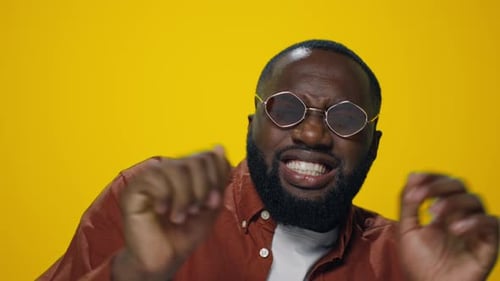 Man Dances Energetically with Expression on Yellow Background