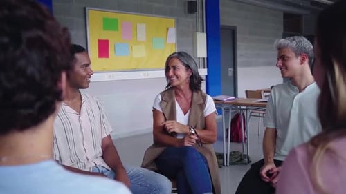 Mature Female Teacher Sitting in Circle with University Students Talking Cheerfully