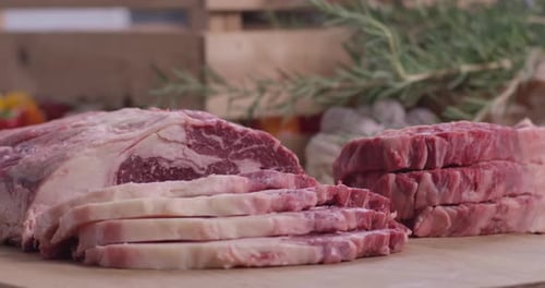 Raw marbled ribeye steak slices and medallions on wooden board Close Up