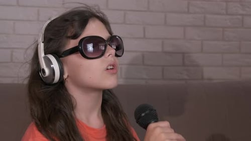 Girl Singing into a Microphone with Headphones and Sunglasses