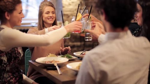Friends toasting drinks and eating in restaurant