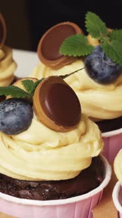 Add to the decoration of chocolate cupcakes with peanut cream mint. Close-up Vertical video.