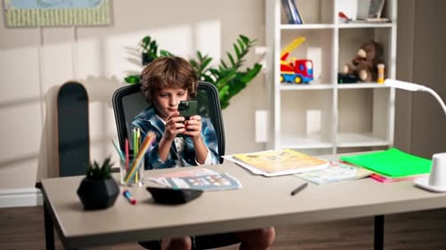 Young Boy with Cell Phone at Desk