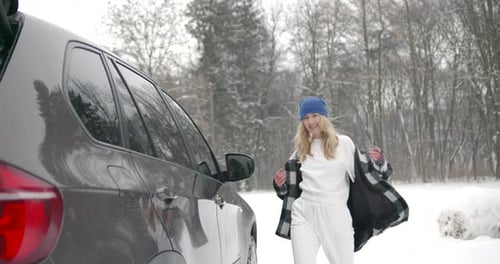 Young Woman with Hot Drink Near Car at Winter Forest