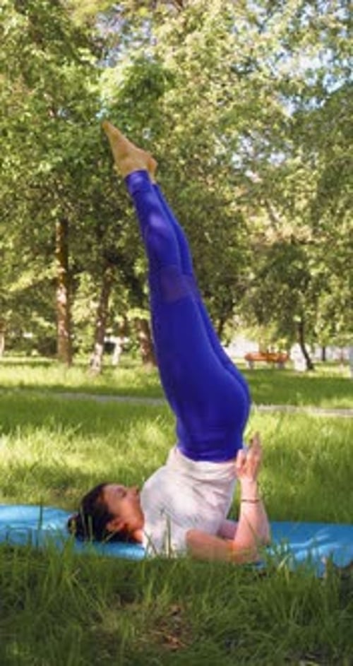 Woman Doing Supported Shoulder Stand Yoga in Park