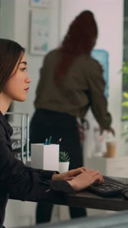 Young Adult Typing at Computer in Modern Office