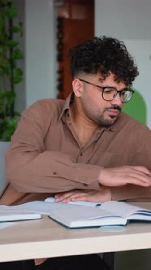 Focused Student Taking Notes While Studying in Modern Library