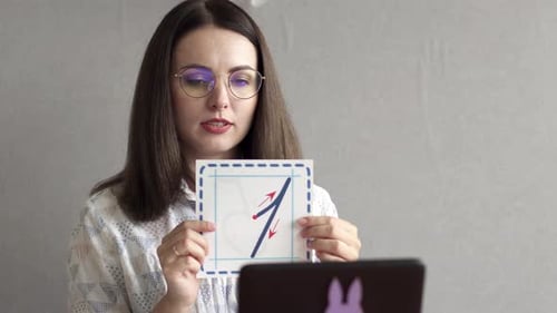 An elementary school teacher teaches a lesson online via a webcam in the classroom.