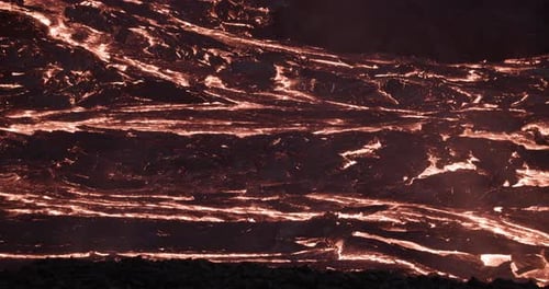 Dark wrinkle surface on slow flowing lava river at night, active volcanic field