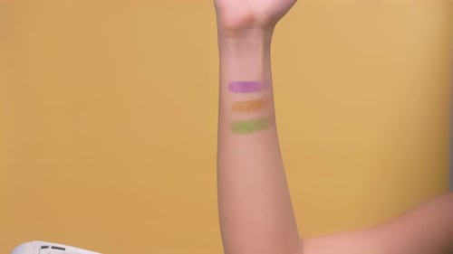 Buntes Make-up auf die Hände aufgetragen. Nahaufnahme von farbenfroher Grundierungskosmetik.