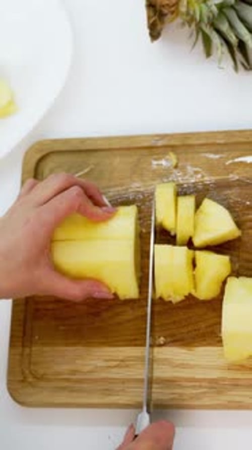 Woman Cutting Pineapple into Cubes on Cutting Board