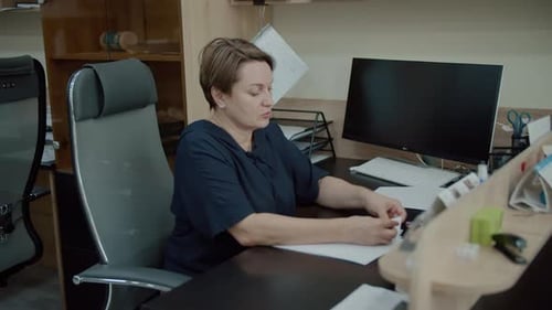 Woman Reviewing Papers at Office Desk