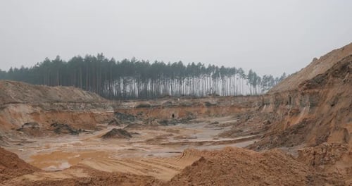 Slopes of Amber Quarry Located Near the Forest with Mining Equipment on Ledges in the Forest and Fog