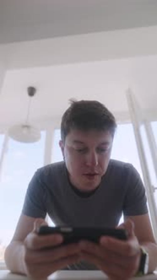 Man Plays Mobile Phone Game Indoors